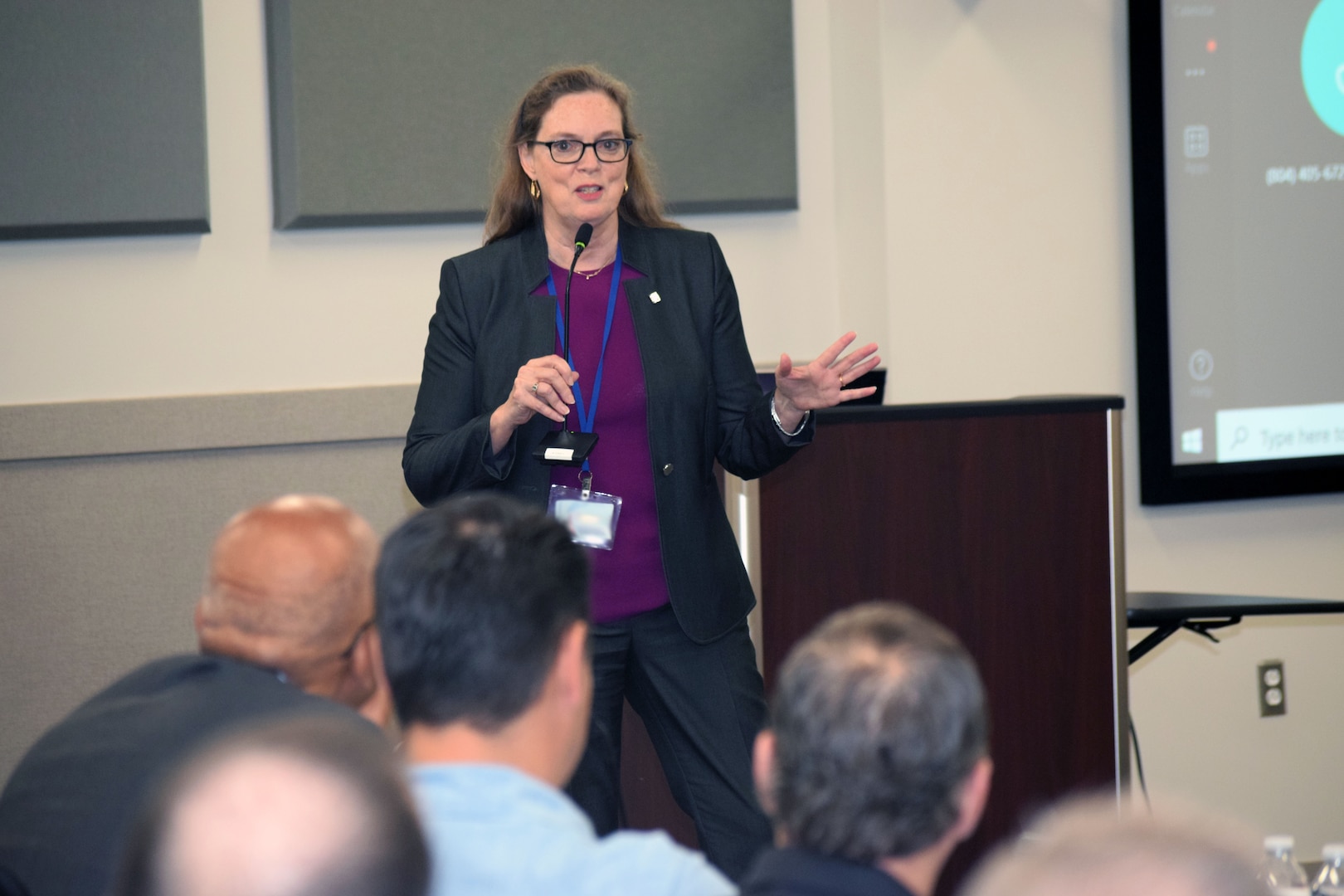 A woman in a gray pantsuit speaking in front of a crowd.