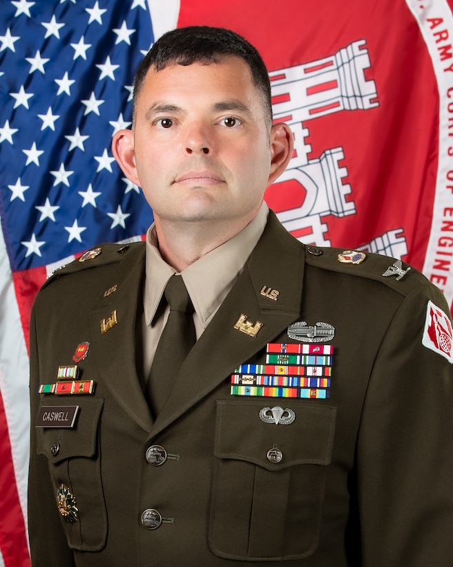 professional bio photo, man in military uniform with US flag and CoE flag in background