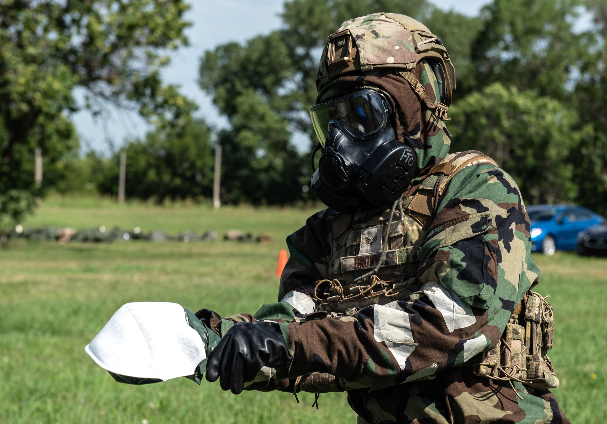 An Airman assigned to the 22nd Civil Engineer Squadron puts on a decontamination glove during the 22nd CES Battle of the Bulls competition July 12, 2023, at McConnell Air Force Base, Kansas. Five teams competed against each other for tent build-up; chemical, biological, radiological, and nuclear training; convoy operations; land navigation; tactical combat casualty care; defensive fighting position and general knowledge during the competition. (U.S. Air Force photo by Staff Sgt. Tryphena Mayhugh)