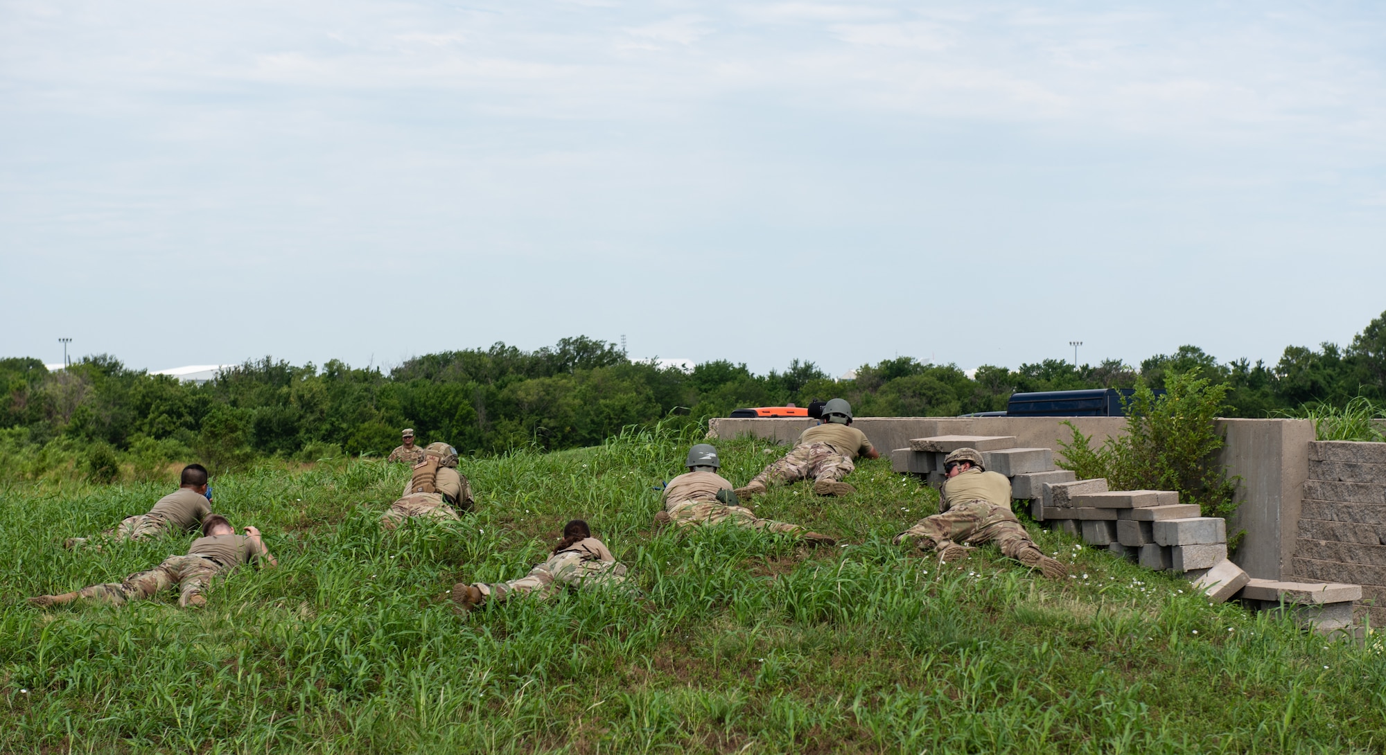 Airmen assigned to the 22nd Civil Engineer Squadron lie in the grass during the 22nd CES Battle of the Bulls competition July 12, 2023, at McConnell Air Force Base, Kansas. Five teams competed against each other for tent build-up; chemical, biological, radiological, and nuclear training; convoy operations; land navigation; tactical combat casualty care; defensive fighting position and general knowledge during the competition. (U.S. Air Force photo by Staff Sgt. Tryphena Mayhugh)