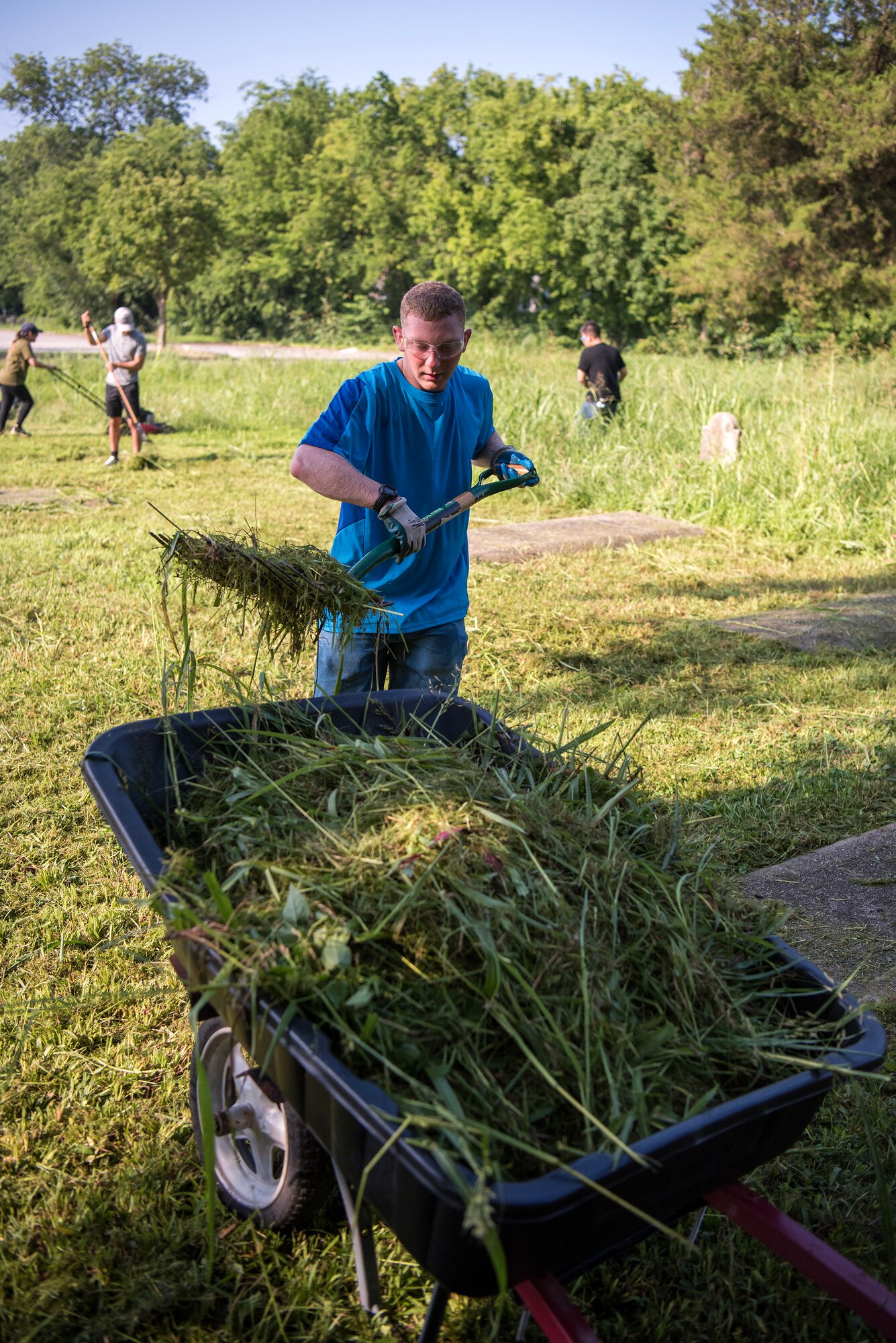 Army Pvt. Christopher Conklin, 1-210 Aviation Regiment, Advanced Individual Training student, gathers grass clippings for disposal at Elmerton Cemetery in Hampton, Virginia, July 8, 2023. These cemeteries are predominately occupied by African Americans, and are two of oldest in Hampton Roads, including service members as far back as World War I. (U.S. Air Force photo by Abraham Essenmacher)