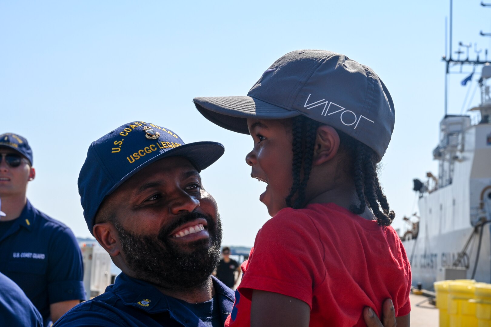 U.S. Coast Guard Chief Petty Officer Jenarius St. Louis, a crew member assigned to USCGC Legare (WMEC 912), holds his son at the unit's return to home port, July 13, 2023, at Coast Guard Base Portsmouth. While underway, Legare’s crew conducted maritime safety and security missions while working to detect, deter and intercept unsafe and illegal maritime migration ventures bound for the United States. (U.S. Coast Guard photo by Petty Officer 3rd Class Kate Kilroy)