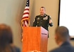 Soldier at podium in front of group of people.