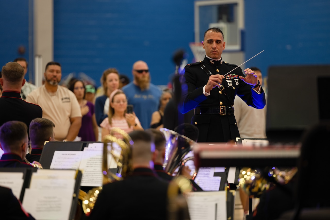 A Marine conducts a band as an audience watches.