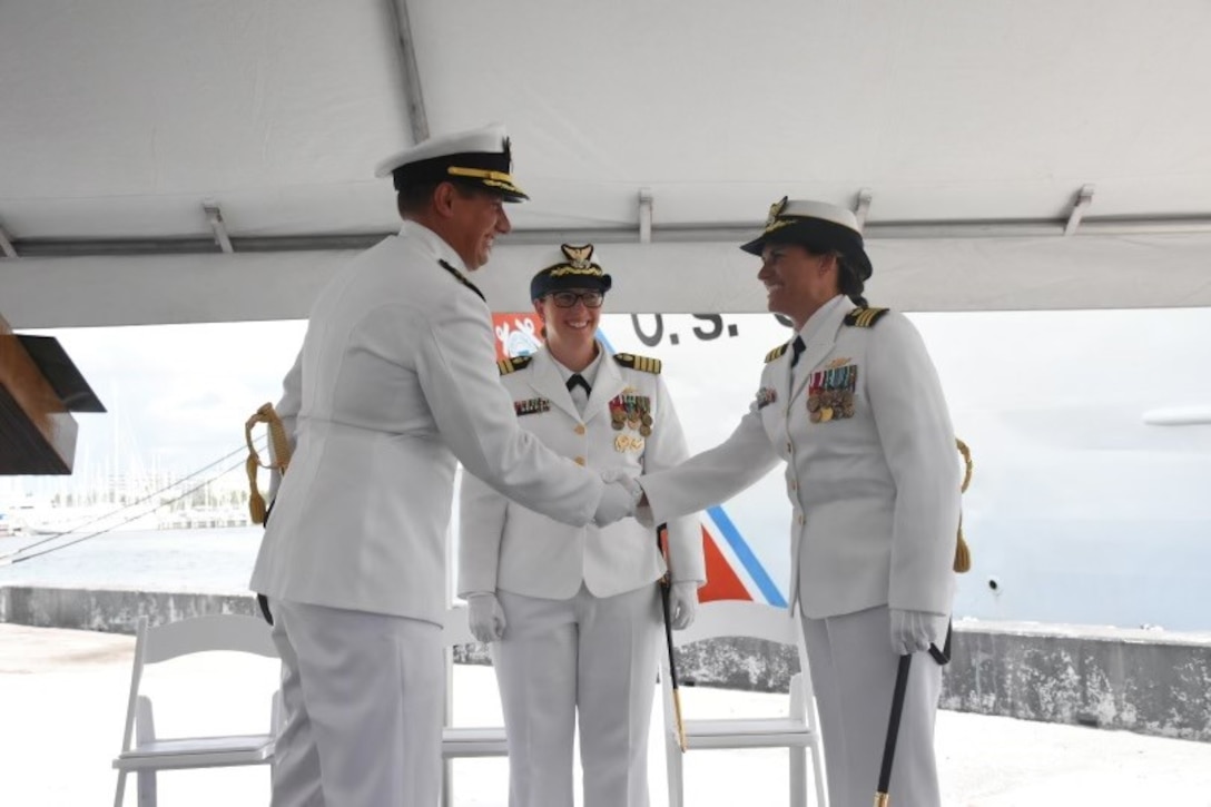 U.S. Coast Guard Cmdr. Karen Kutkiewicz, right, shakes hands with Cmdr. Cory Riesterer, left, at the USCGC Venturous' (WMEC 625) change of command ceremony, July 13, 2023, at Coast Guard Sector St. Petersburg. Capt. Kristen Serumgard, middle, chief of Operational Forces of Coast Guard Atlantic Area, presided over the ceremony. (U.S. Coast Guard photo courtesy of Venturous)
