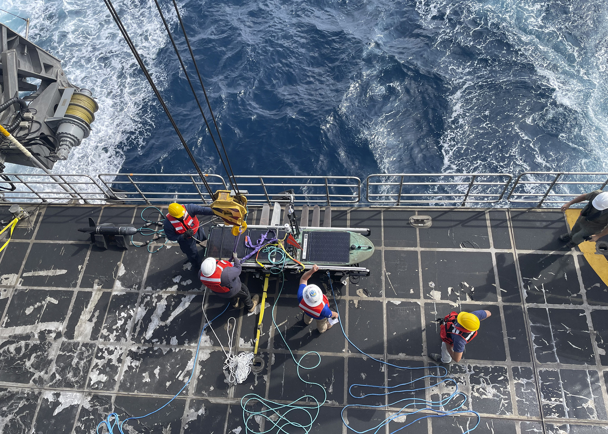 Sailors and civil service  mariners launch a Wave Glider unmanned surface vessel from USNS Burlington (T-EPF 10).