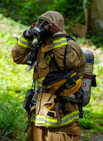 A Federal Fire Department Firefighter firefighter puts on dons firefighting gear during a spill response exercise on Joint Base Pearl Harbor-Hickam, Hawaii, July 13, 2023.