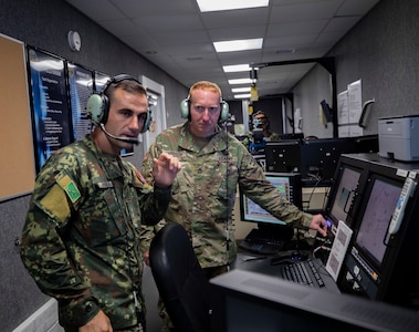 Albanian Capt. Egluent Rika, left, and New Jersey Army National Guard Sgt. 1st Class James Harrison discuss a combat convoy exercise in a virtual reality simulator at Joint Base McGuire-Dix-Lakehurst on July 9.