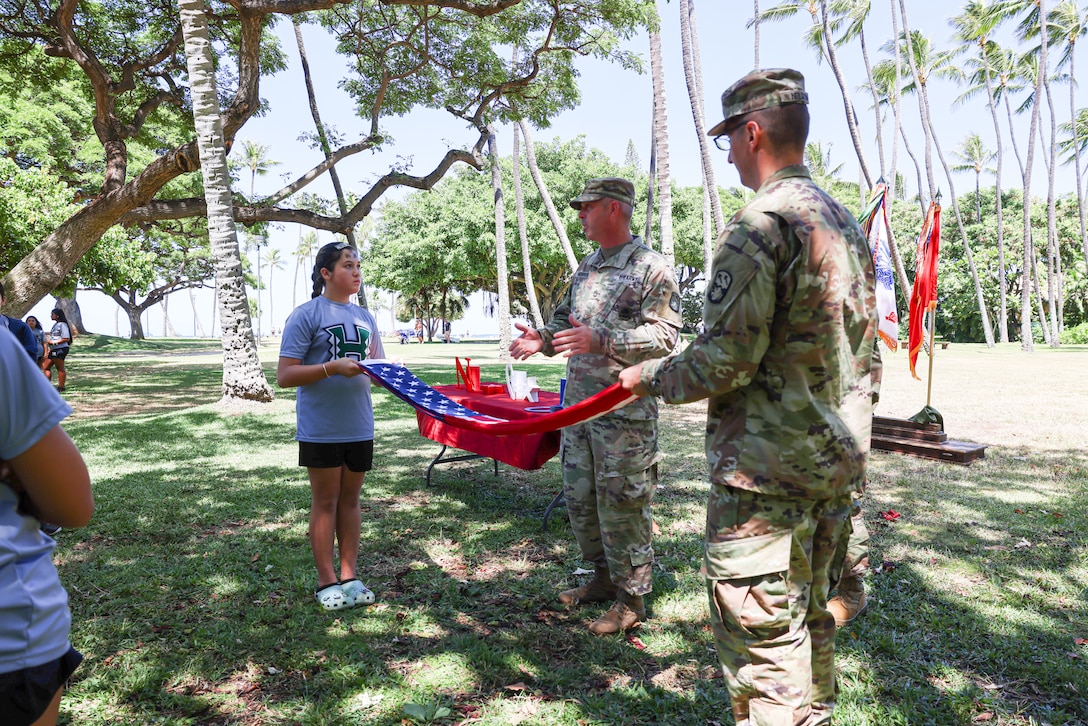 Youth Impact program participants learn how to fold the U.S. flag during Army Day, Fort DeRussy Military Reservation, Hawaii, July 14, 2023. The Hawaii Youth Impact Program brings together service members, University of Hawaii faculty and local volunteers to cultivate leadership, discipline and mentorship skills among aspiring youth.