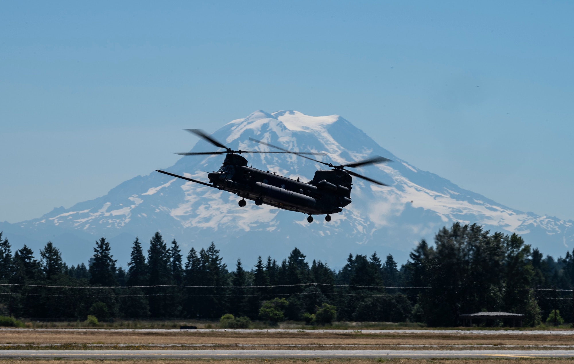 A U.S. Army MH-47 Chinook flies above the McChord Field flightline while practicing for the Joint Base Lewis-McChord Airshow and Warrior Expo at JBLM, Washington, July 14, 2023. The mission of the JAWE is to foster goodwill to educate and familiarize attendees with the people, mission, and equipment of the Air Force, Army, and other Armed Services while continuing to provide installation-wide mission support. (U.S. Air Force photo by Staff Sgt. Rachel Williams)