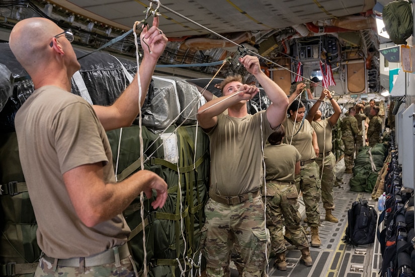 Soldiers secure cargo in the back of a large military aircraft.