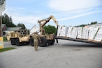 U.S. Army Staff Sgt. John Hackley, truck driver, Alpha Company, 186th Brigade Support Battalion, 86th Infantry Brigade Combat Team (Mountain), Vermont Army National Guard, guides a HEMTT-LHS delivering water, Marshfield, Vt., July 13, 2023.