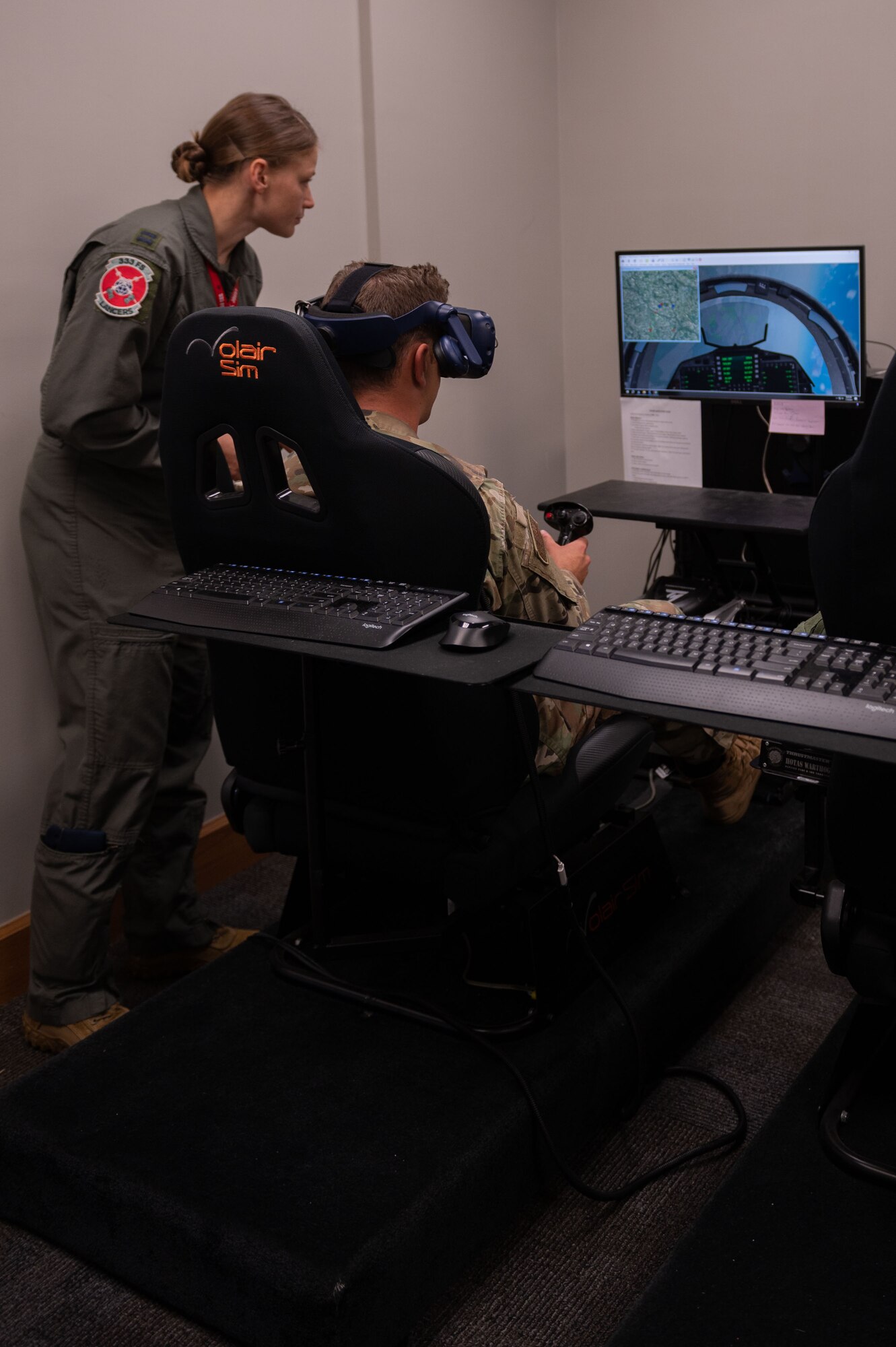 Capt. Cecilia Tumas, 333rd Fighter Squadron pilot, helps a cadet with controllers on a virtual reality flight simulator during an Operation Air Force visit at Seymour Johnson Air Force Base, North Carolina, July 10, 2023. Military education and visits like these play a critical role in preparing cadets to become leaders in the cadet wing and later in the U.S. Air Force and Space Force. (U.S. Air Force photo by Airman 1st Class Rebecca Sirimarco-Lang)