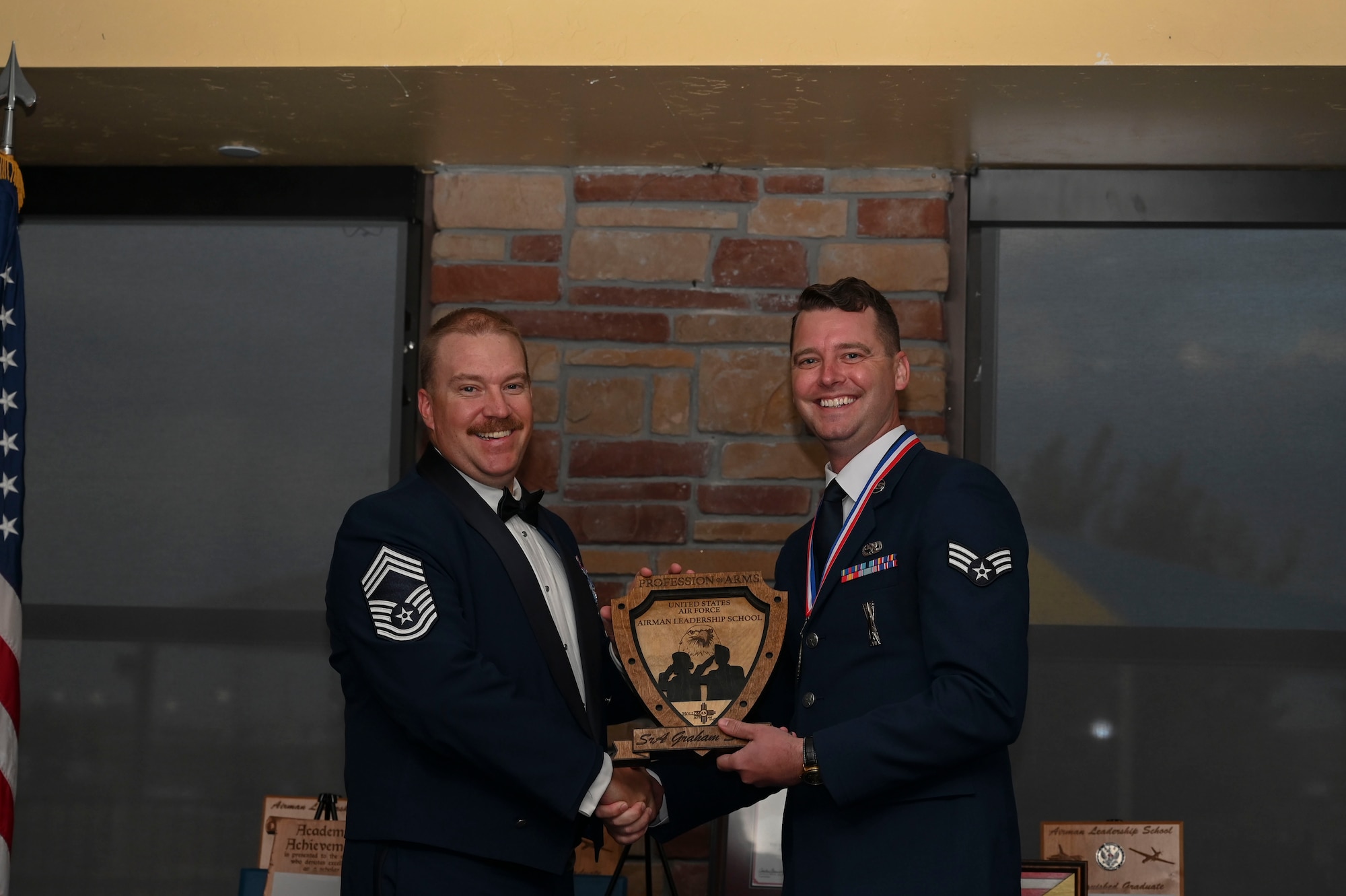 U.S. Air Force Senior Airman Graham Swain, Airman Leadership School graduate, right, receives the profession of arms award during the graduation of ALS class 23-F at Holloman Air Force Base, New Mexico, July 14, 2023. The profession of arms award recognizes the student who most embodies the profession of arms, which is demonstrated with a comprehensive understanding of the warrior ethos, oath of enlistment, and the airman’s creed. (U.S. Air Force photo by Airman 1st Class Isaiah Pedrazzini)
