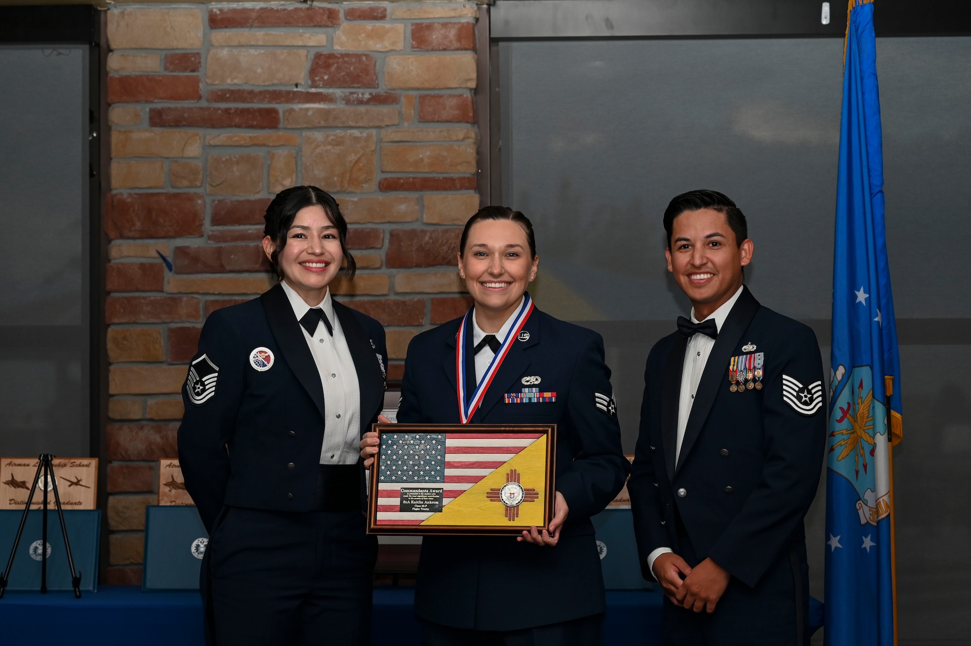 U.S. Air Force Senior Airman Kaitlin Ankrom, Airman Leadership School graduate, middle, receives the Commandant’s Award during the graduation of ALS class 23-F at Holloman Air Force Base, New Mexico, July 14, 2023. The Commandant’s award is selected by the ALS commandant and is presented to the student who best demonstrates the characteristics of an effective leader. (U.S. Air Force photo by Airman 1st Class Isaiah Pedrazzini)