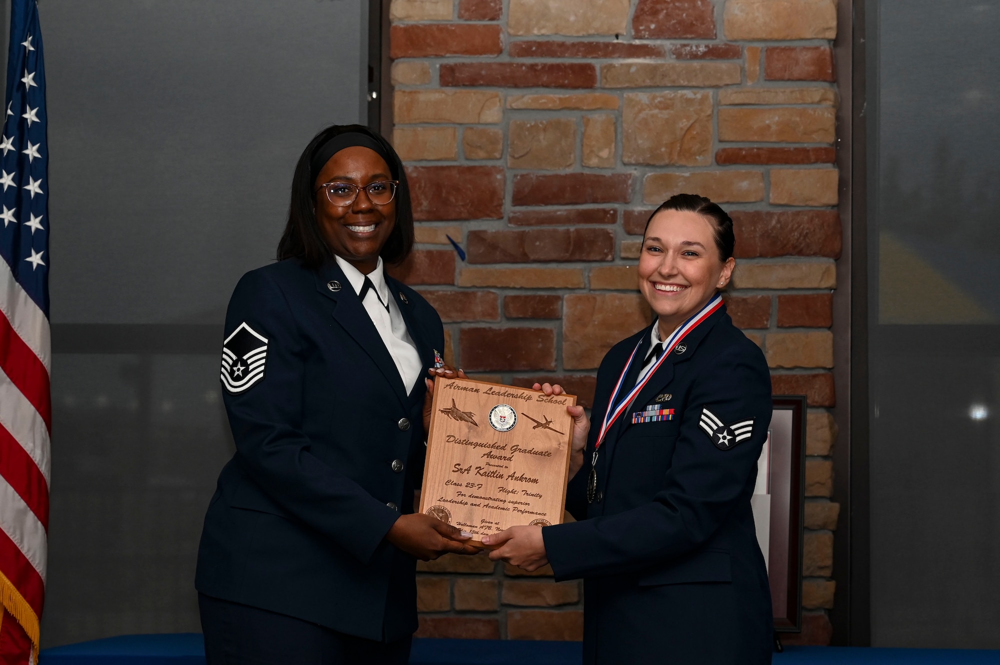 U.S. Air Force Senior Airman Kaitlin Ankrom, Airman Leadership School graduate, right, receives the distinguished graduate Award during the graduation of ALS class 23-F at Holloman Air Force Base, New Mexico, July 14, 2023. The distinguished graduate award is presented to the top ten percent of graduates for their performance in academic evaluations and demonstration of leadership. (U.S. Air Force photo by Airman 1st Class Isaiah Pedrazzini)
