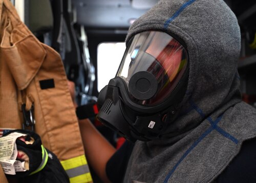 Justin Nava, 17th Civil Engineer Squadron firefighter, gears up at the fire station, Goodfellow Air Force Base, Texas, June 30, 2023. The mask firefighters wear is connected to a self-contained breathing apparatus consisting of a fresh tank of air, a harness, and pressure regulators. When a firefighter is wearing all of their gear, for an active fire situation, it can weigh between 35 and 80 pounds. (U.S. Air Force photo by Airman 1st Class Madison Collier)