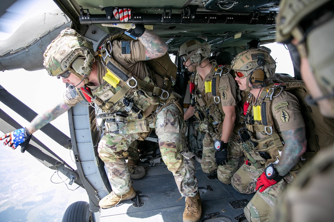 Soldiers look out of a military aircraft while in flight.