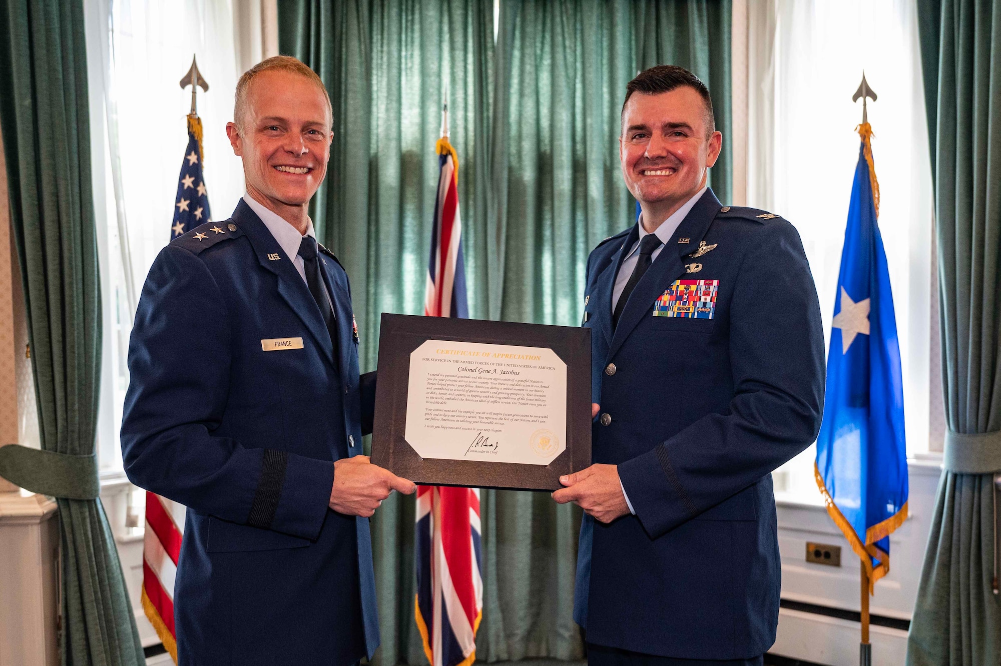 Mrs. Heather Jacobus, former 100th Air Refueling Wing key spouse, pins a retirement pin on U.S. Air Force Col. Gene Jacobus, who retired at Royal Air Force Mildenhall, England, July 17, 2023. Jacobus retired after 23 years of service to the Department of Defense. (U.S. Air Force photo by Senior Airman Viviam Chiu)