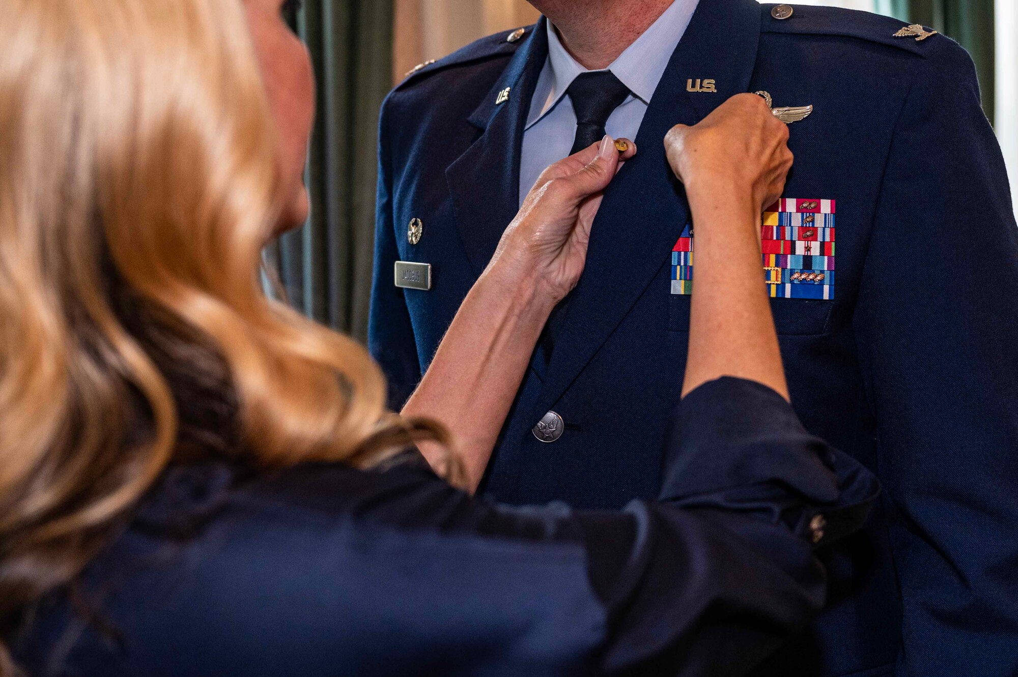 Mrs. Heather Jacobus, former 100th Air Refueling Wing key spouse, pins a retirement pin on U.S. Air Force Col. Gene Jacobus, who retired at Royal Air Force Mildenhall, England, July 17, 2023. Jacobus retired after 23 years of service to the Department of Defense. (U.S. Air Force photo by Senior Airman Viviam Chiu)