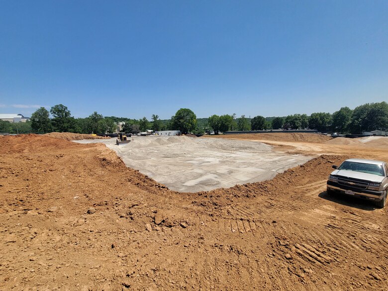 A slab of concrete is surrounded by dirt with trees and a blue sky in the background.