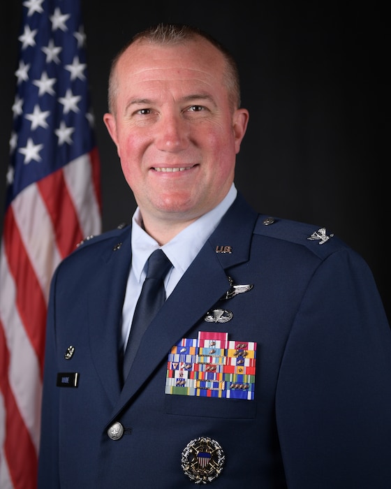 photo of uniformed US military member with a US flag in the background.