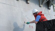 Engineer Bill Manning primes an overboard discharge on the hull of USS Kidd (DDG 100) in Everett, Wash., on June 21, before attaching the 3D-printed overboard discharge scupper. (U.S. Navy photo provided by Dr. Maureen Foley)
