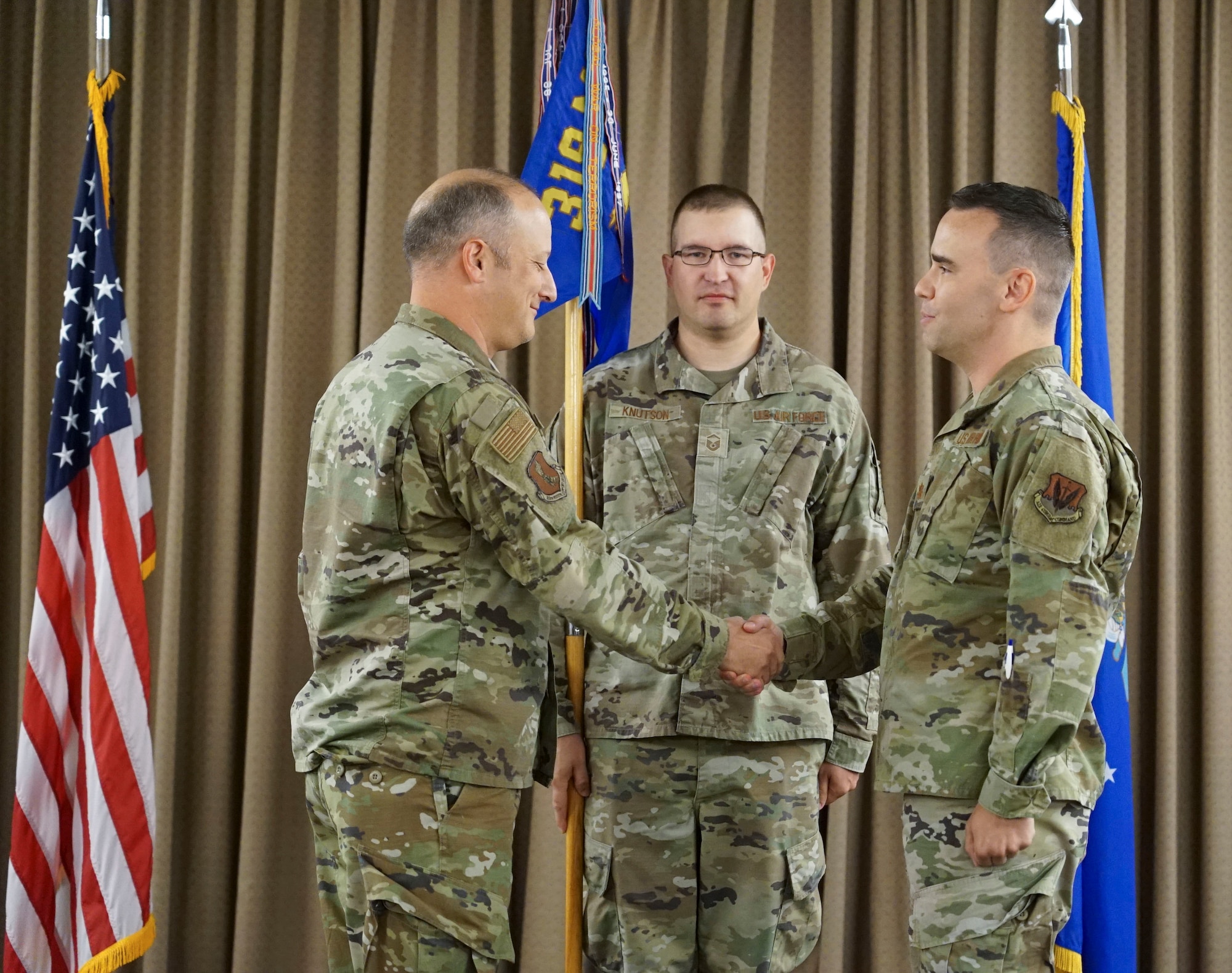 U.S. Air Force Col. David Castor shakes hands with Air Force Maj. Andrew Beidler.