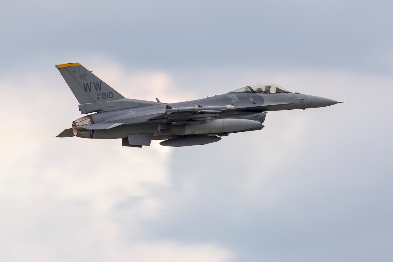 A military fighter jet soars through the sky.