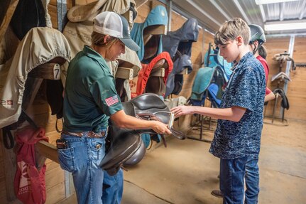 Children look at saddles.