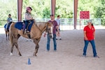 Child rides a horse while her father and instructor watch.