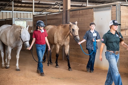 Two children lead horse from a barn.