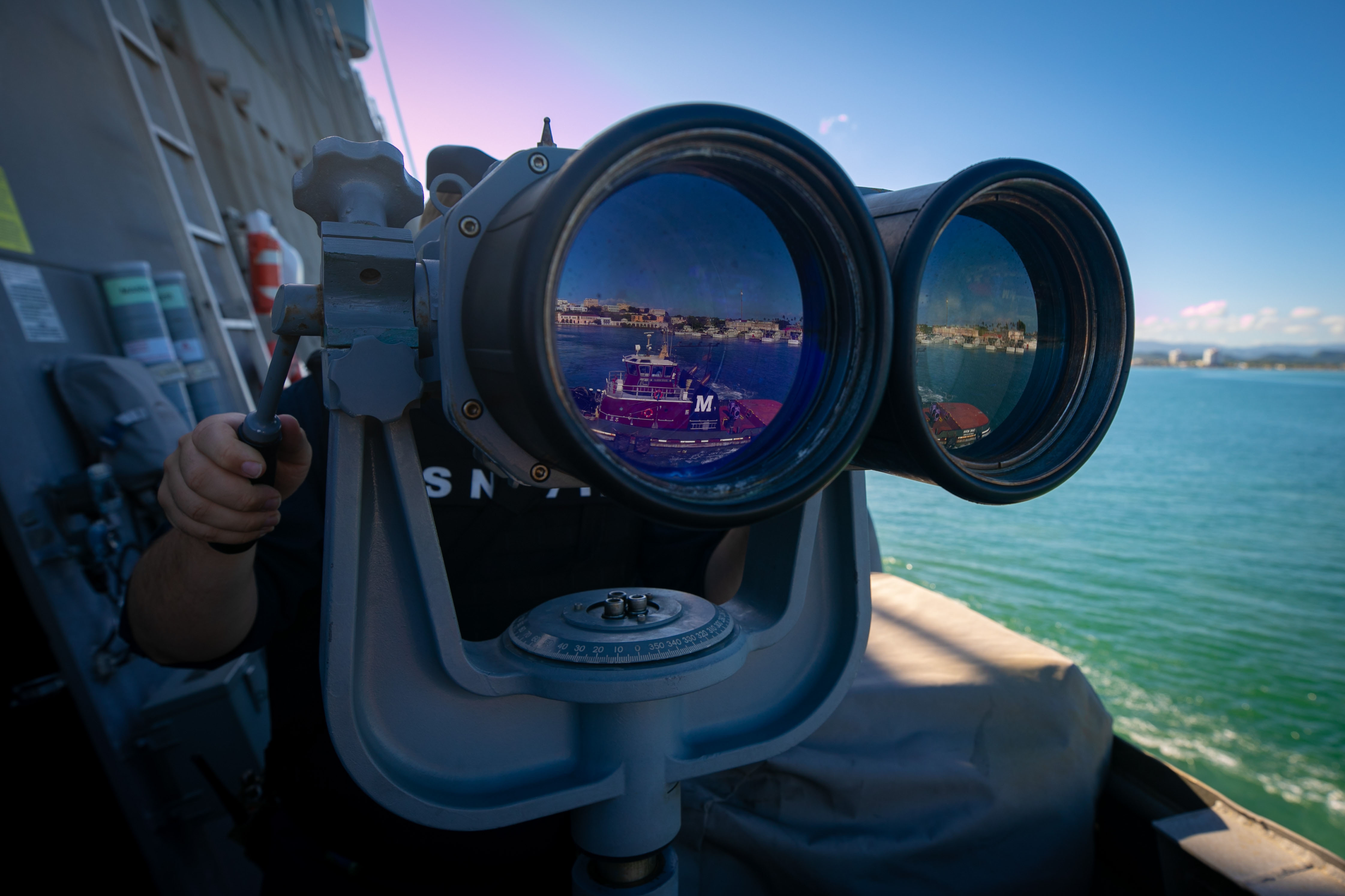 SAN JUAN, Puerto Rico - (Nov. 27, 2021) – A Sailor assigned to the Freedom-variant littoral combat ship USS Sioux City (LCS 11) looks through the ship’s binoculars during an outbound sea and anchor detail from San Juan, Puerto Rico, Nov. 27, 2021. Sioux City is deployed to the U.S. 4th Fleet area of operations to support Joint Interagency Task Force South’s mission, which includes counter-illicit drug trafficking missions in the Caribbean and Eastern Pacific. (U.S. Navy photo by Mass Communication Specialist 3rd Class Juel Foster/Released)