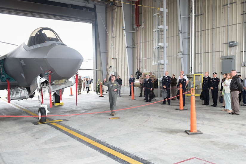 People look at a plane in a hangar.