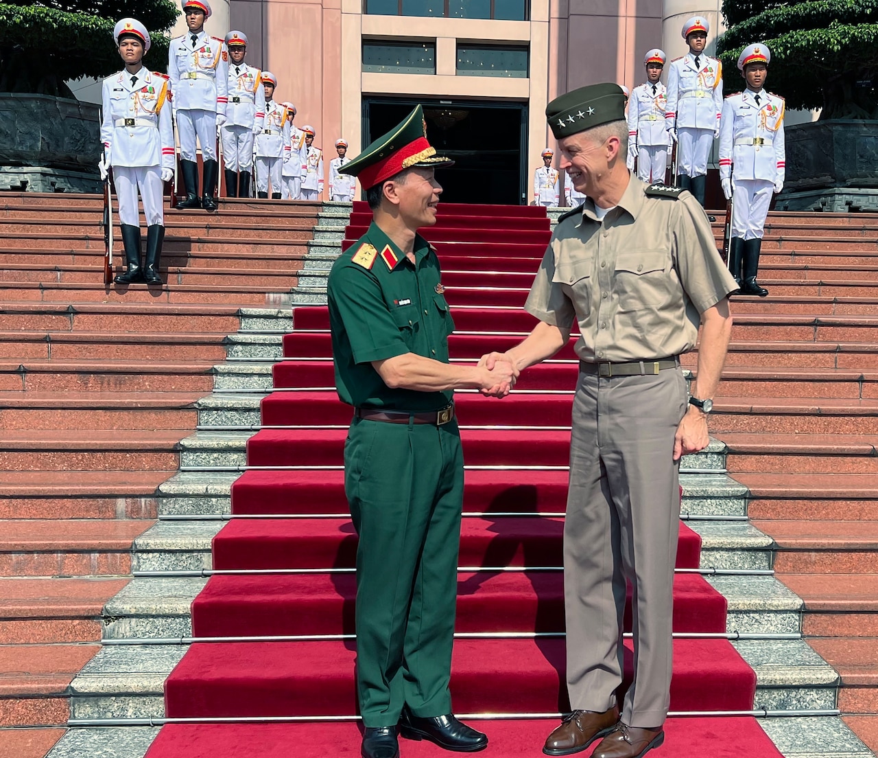 Two men in uniform from the United States and Vietnam shake hands.
