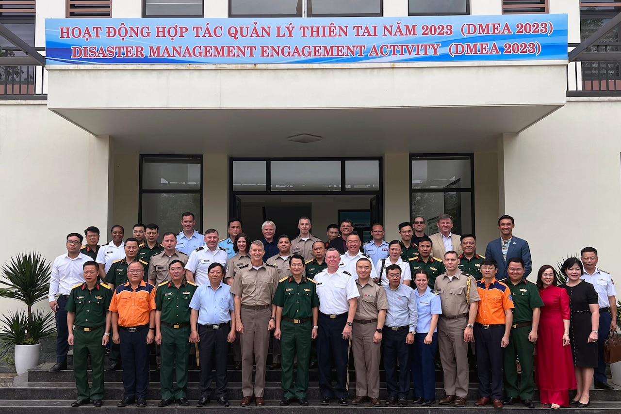 Men and woman stand together on steps in front of a building for a group photo.