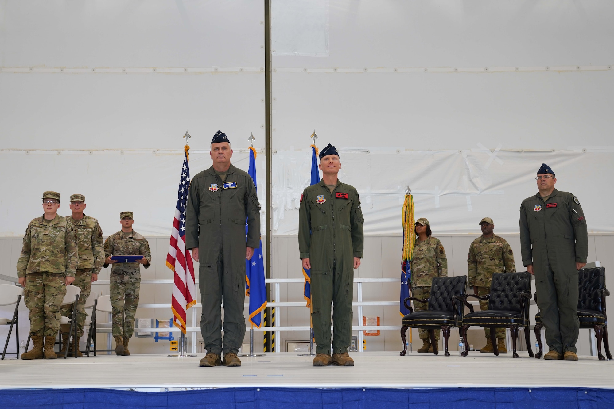 People in military uniforms stand at attention on a stage.