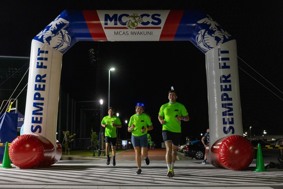 Members of Marine Corps Air Station Iwakuni community cross the finish line during a neon night run at the Atago Sports Complex, Iwakuni, Japan, June 24, 2023. The neon night run event, hosted by Marine Corps Community Services, consisted of warmup Zumba dancing, a 5K family fun run, and raffle drawings and was and. (U.S. Marine Corps Photo by Cpl. Calah Thompson)
