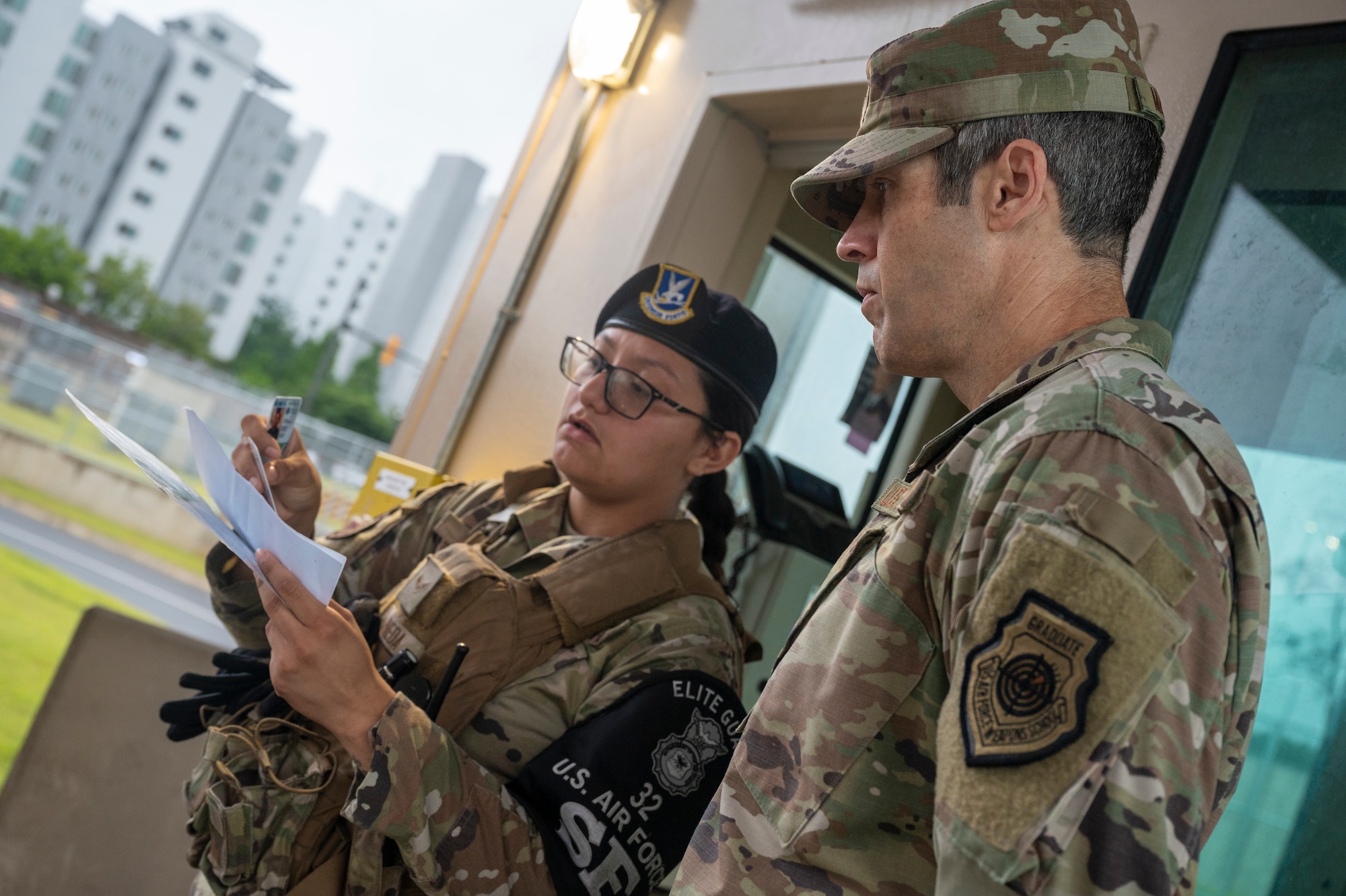 U.S. Air Force Col. William McKibban, right, 51st Fighter Wing commander, receives instructions on checking IDs from Airman 1st Class Esbeidy Pineda, 51st Security Forces Squadron Defender, at the main gate on Osan Air Base, Republic of Korea, June 30, 2023. Every person that comes through the gate must present an ID card to be scanned and or thoroughly inspected to ensure they have installation access before proceeding on base. (U.S. Air Force photo by Senior Airman Aaron Edwards)