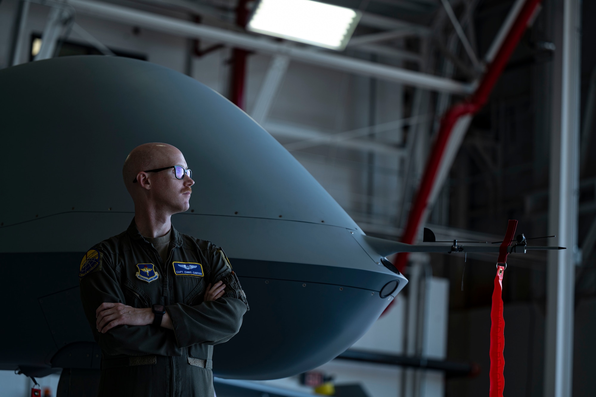 U.S. Air Force Capt. Christopher Carter, 491st Attack Squadron MQ-9 Reaper instructor pilot, poses in front of an MQ-9 at Hancock Field Air National Guard Base, New York, June 22, 2023. The 491st ATKS instructors train MQ-9 student pilots and sensor operators in real-world combat circumstances that will be present in operational environments. (U.S. Air Force photo by Airman 1st Class Isaiah Pedrazzini)