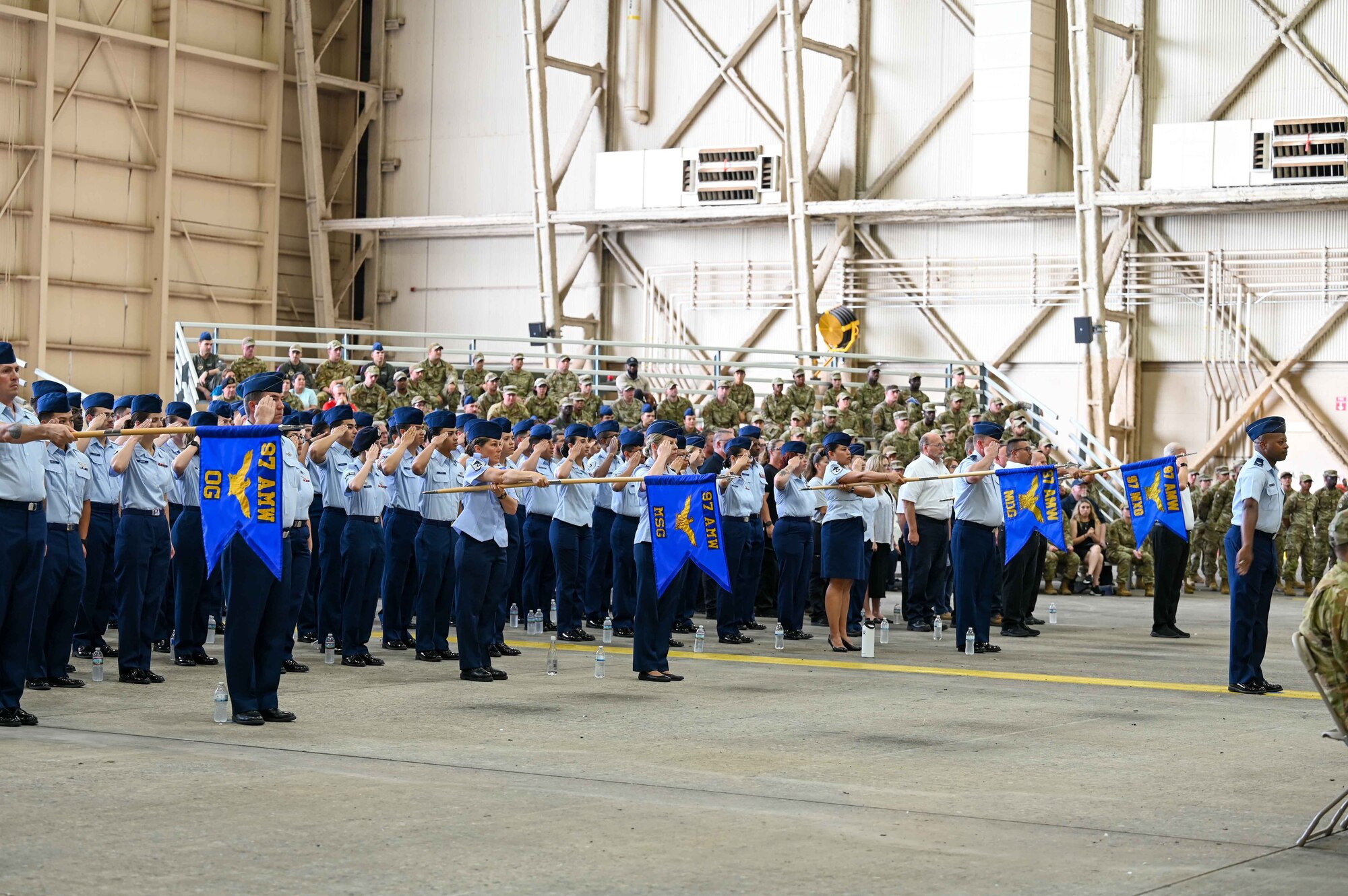 A formation salutes the flag during the playing of a national anthem at the wing change of command at Altus Air Force Base, Oklahoma, July 14, 2023. Col. Jeffrey Marshall assumed command of the 97th Air Mobility Wing during the ceremony. (U.S. Air Force photo by Airman 1st Class Kari Degraffenreed)