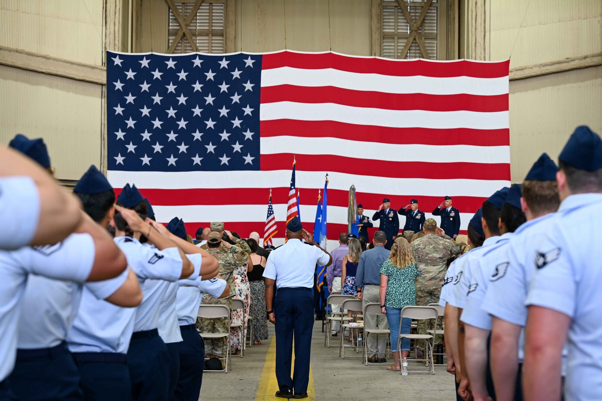 A formation salutes the flag while the national anthem plays during the wing change of command at Altus Air Force Base, Oklahoma, July 14, 2023. Col. Jeffrey Marshall assumed command of the 97th Air Mobility Wing during the ceremony. (U.S. Air Force photo by Airman 1st Class Kari Degraffenreed)