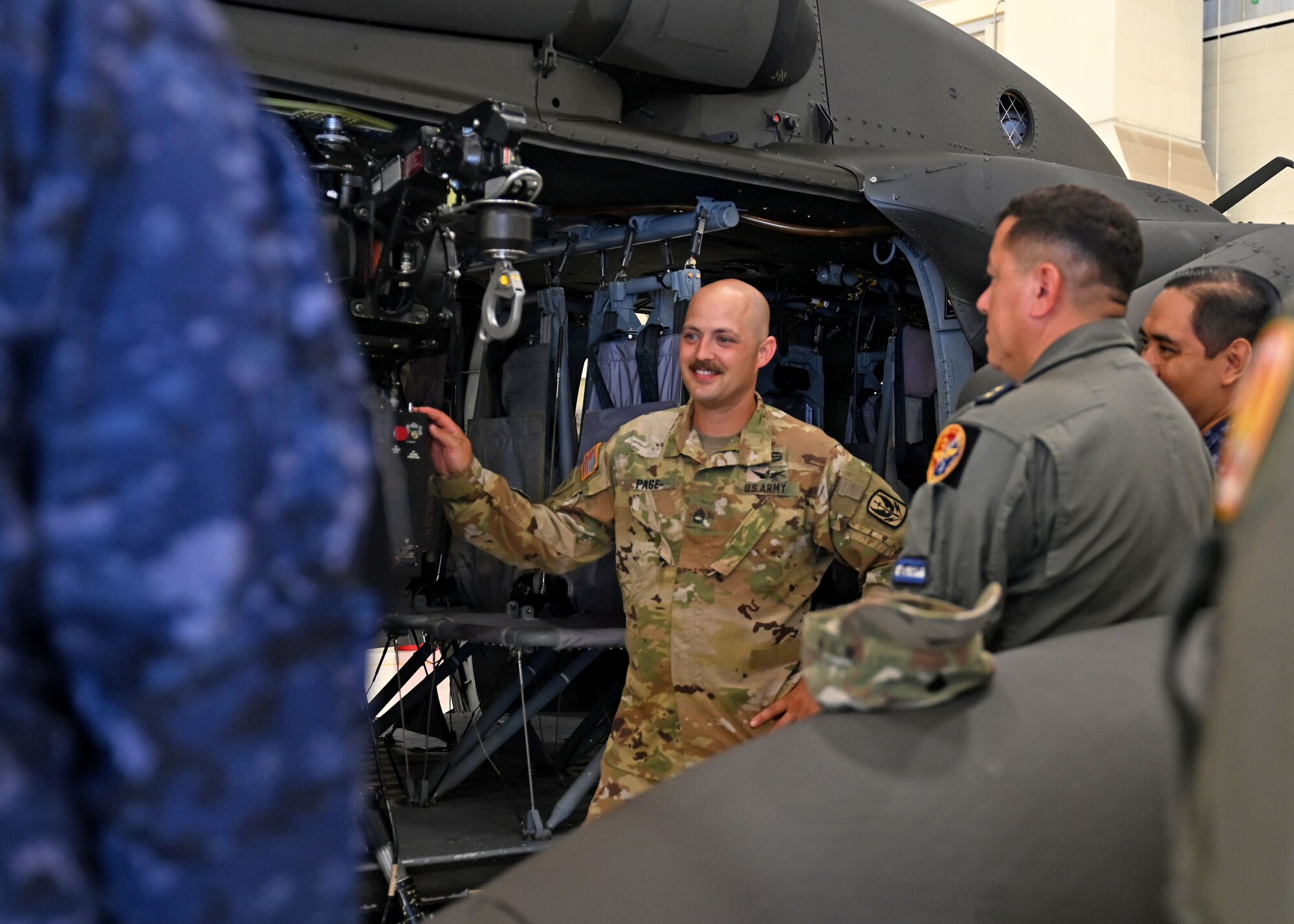 Sgt. 1st Class Keith Page, a production controller with Alpha Company, 1-169th Aviation Regiment, leads a discussion with seven military guests from El Salvador Black Hawk hoist operation and rescue techniques at the Army Aviation Support Facility on July 11 in Concord.