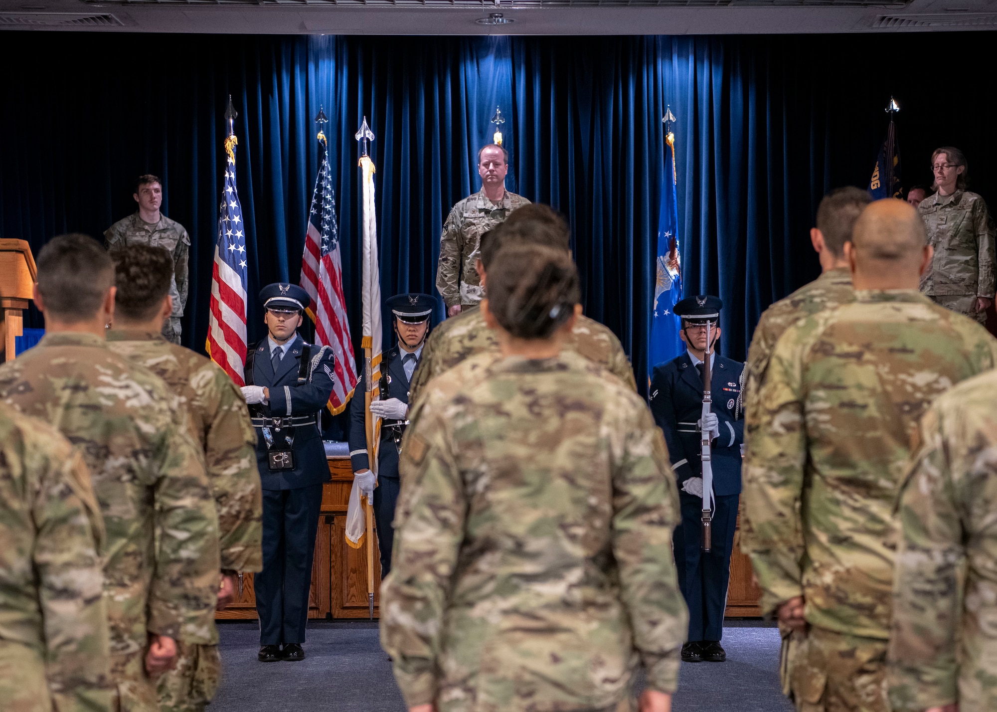 Military members stand at attention while the Base honor Guard performs the colors.