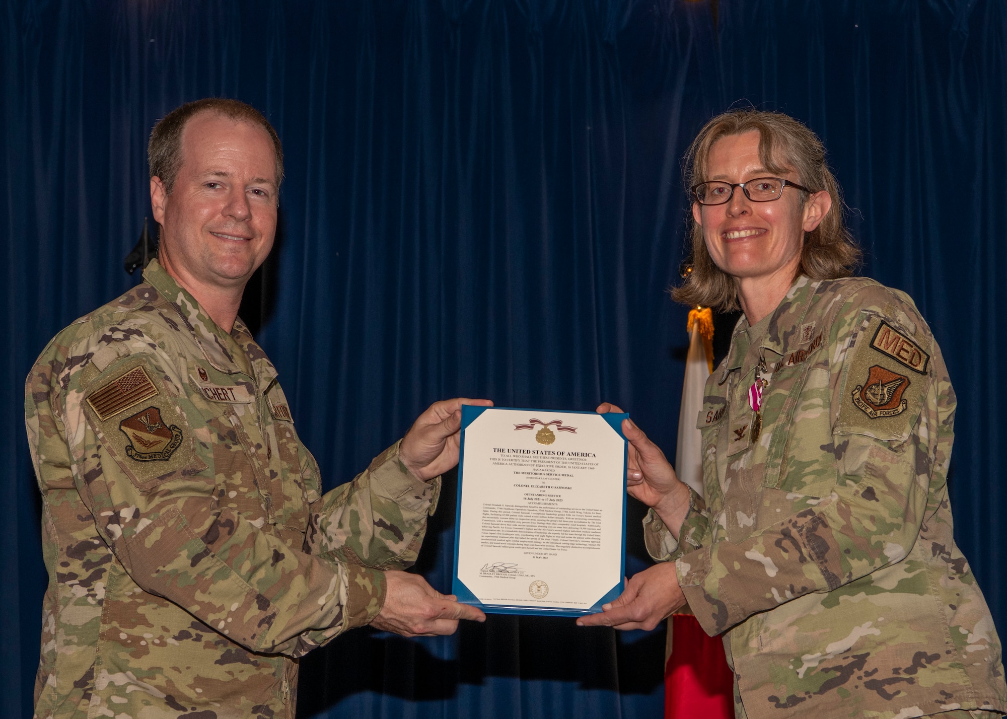 A military man hand a military woman an award.