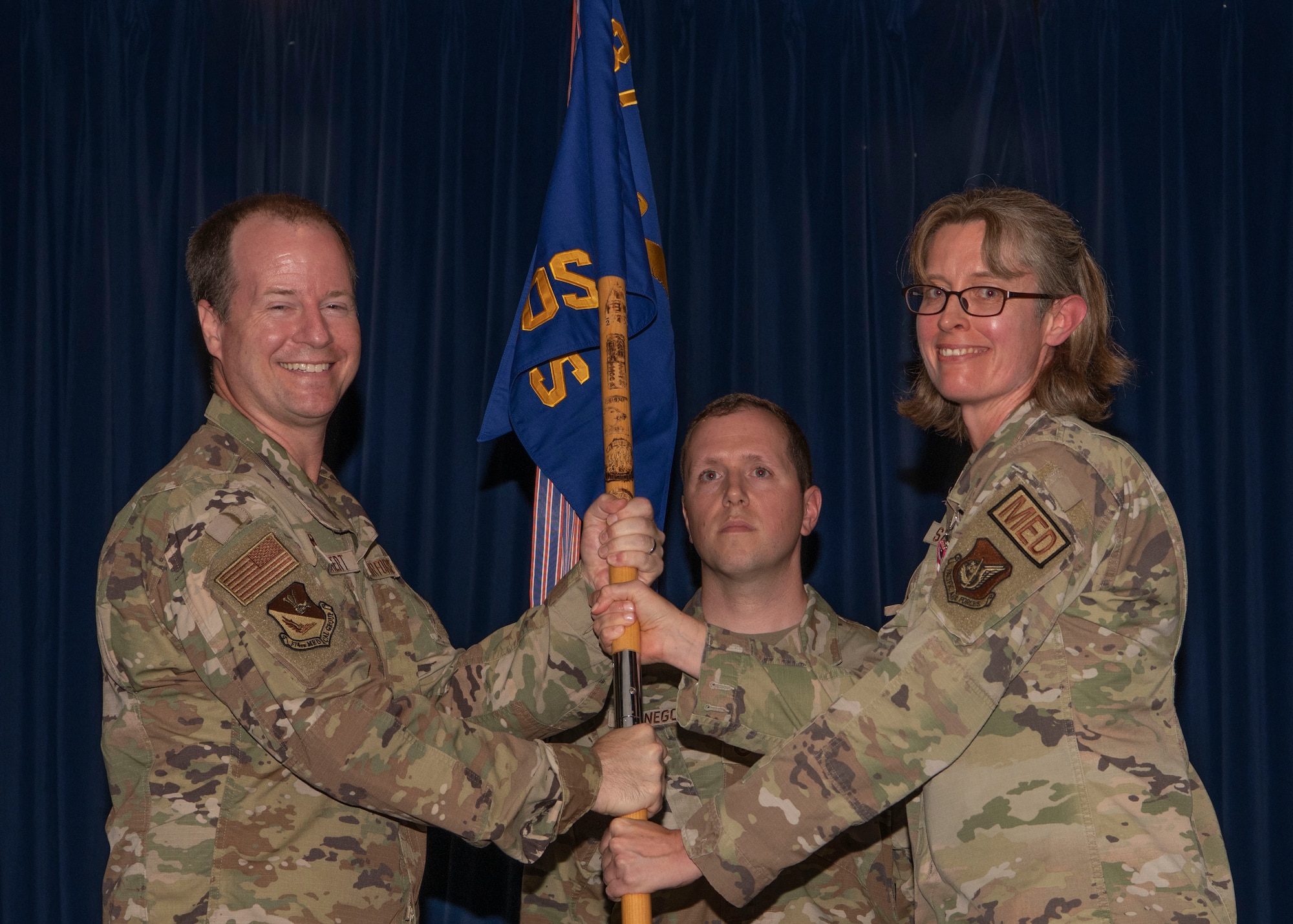 Two military members hold a guidon.