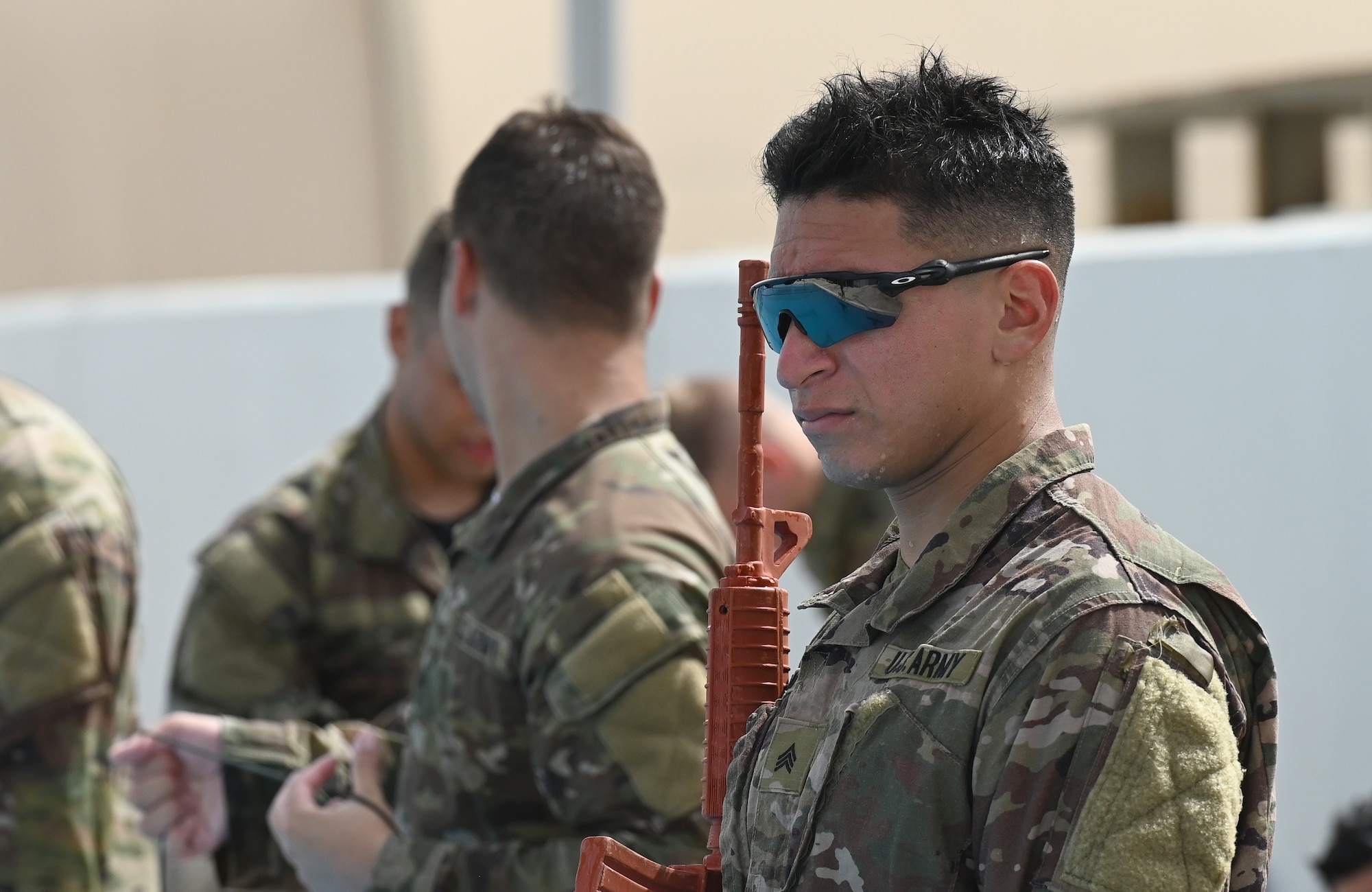A photo a man standing next to a pool with a simulated rifle.