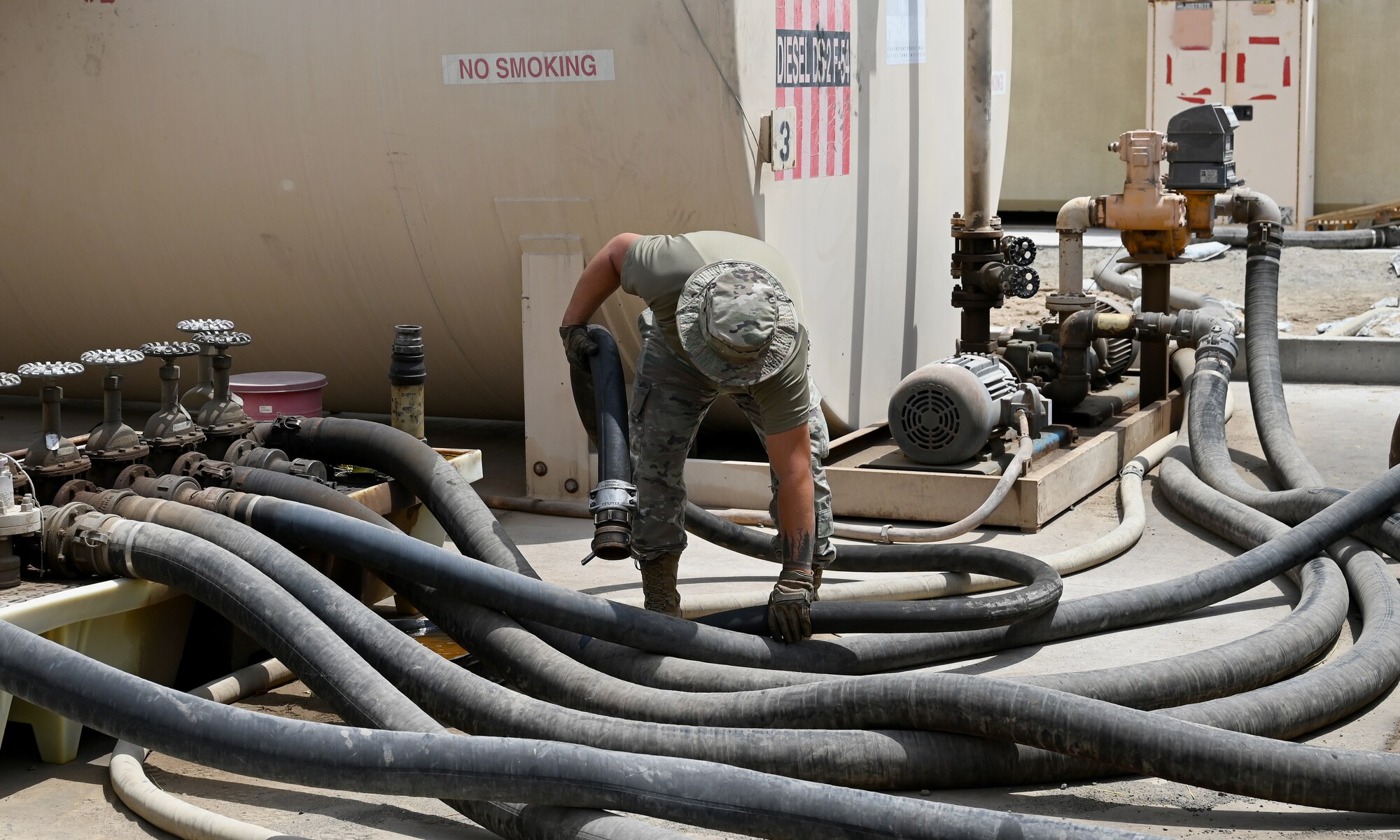 A photo of a man picking up a hose.