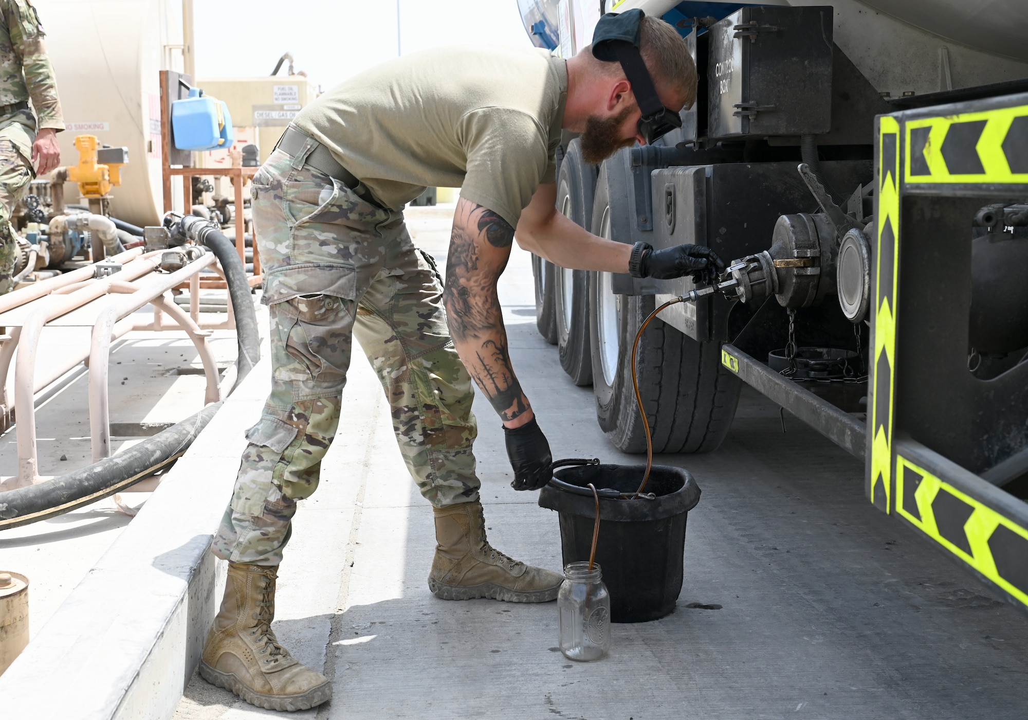 A photo of a man filling up a jar with fuel.