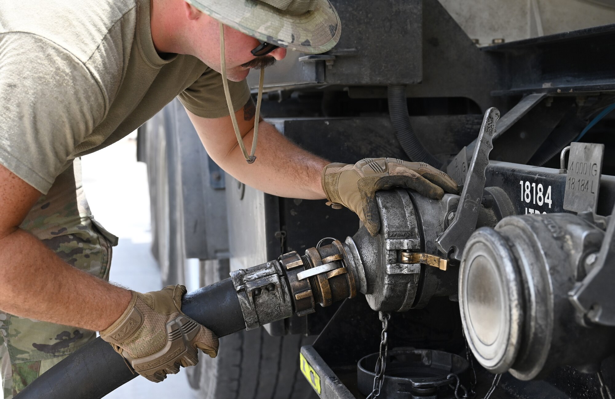 A photo of a man connecting a hose to a tank truck.